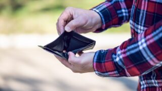 person in red blue and white plaid long sleeve shirt holding black leather bifold wallet