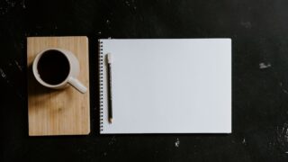 A cup of coffee and notebook with a pencil
